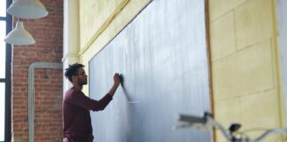 De professors i alumnes man writing on a blackboard